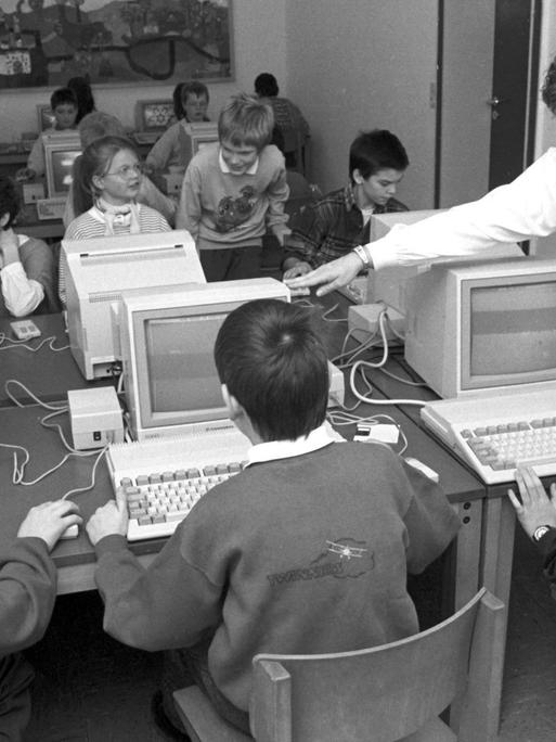 Eine Lehrerin unterrichtet an einer Grundschule in den 1980er-Jahren an Computern.