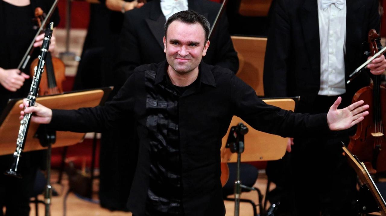 Der Klarinettist Jörg Widmann steht beim Musikfestival Heidelberger Frühling im April 2016 auf der Bühne. In der rechten Hand hält er eine Klarinette und er bedankt sich beim Publikum. 