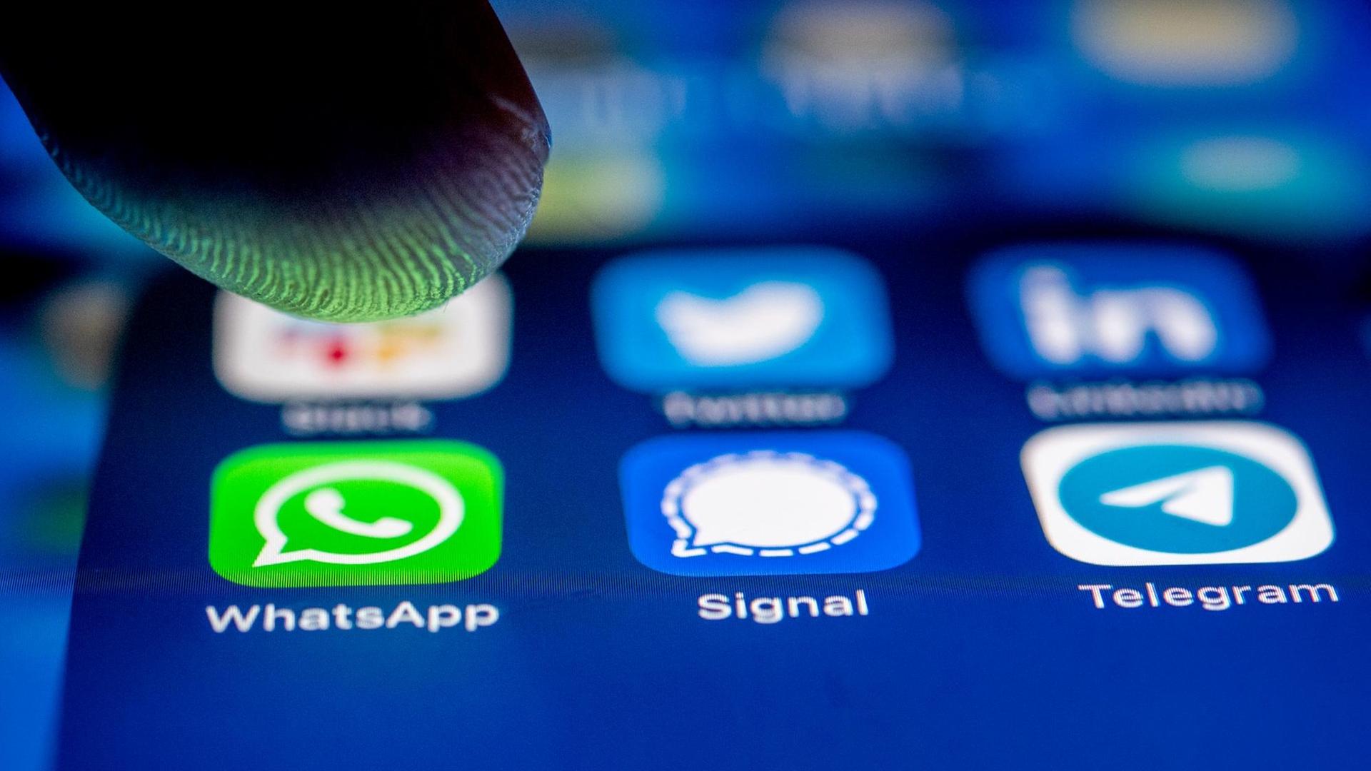 Die App-Logos fuer die Messenger WhatsApp, Signal und Telegram auf einem iPhone Smartphone.