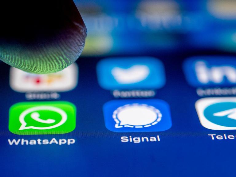 Die App-Logos fuer die Messenger WhatsApp, Signal und Telegram auf einem iPhone Smartphone.