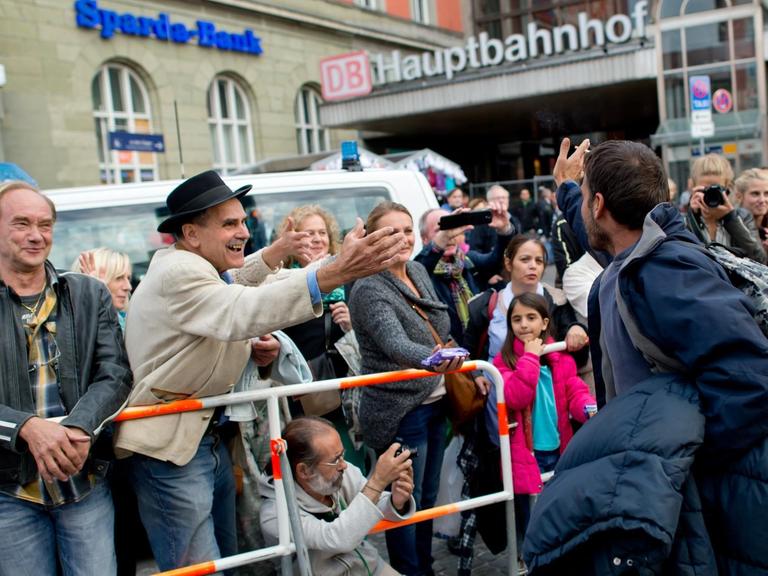 Flüchtlinge werden am Hauptbahnhof München von Menschen hinter einer Absperrung begrüßt.