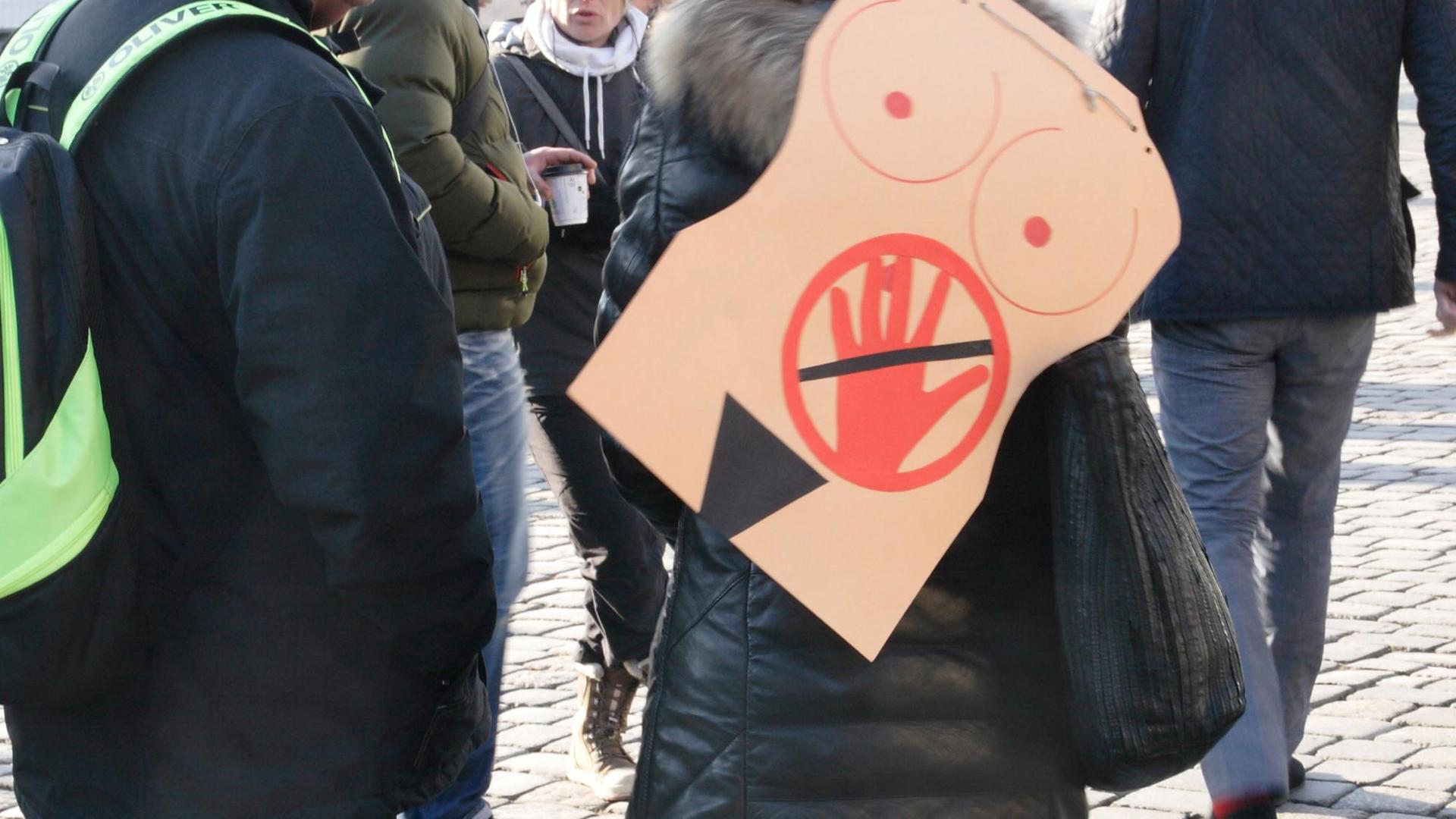 In Dresden auf dem Neumarkt trägt eine Frau auf einer Veranstaltung auf dem Ruecken ein symbolisches Bild gegen sexuelle Belästigung oder sexuelle Uebergriffe