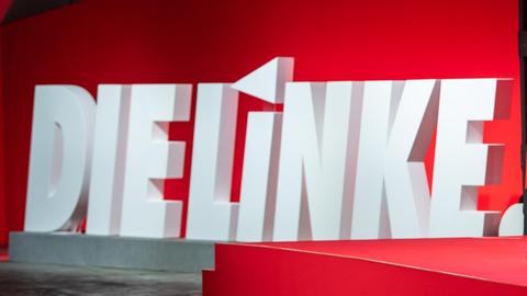 Die Worte "Die Linke" stehen in weiß auf rotem Grund hinter einem Rednerpult.