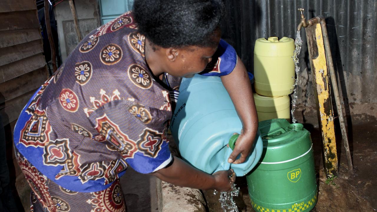 Eine Frau füllt Wasser in Plastikkanister an einem öffentlichen Brunnen in der kenianischen Hauptstadt Nairobi.