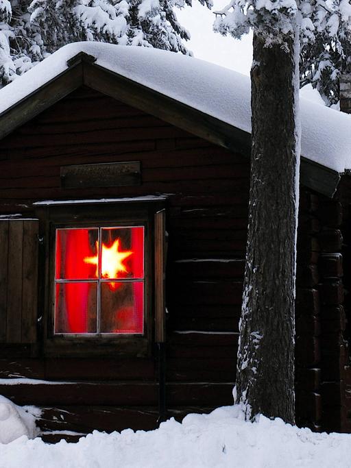 Blockhütte in einem verschneiten Wald in Gällivare - Schwedisch-Lappland