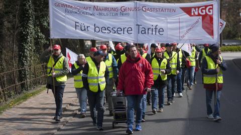 Mitarbeiter der Flensburger Brauerei halten während eines Warnstreiks Transparente mit der Forderung nach besseren Tarifen hoch