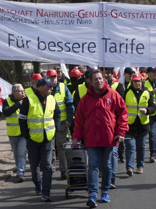 Mitarbeiter der Flensburger Brauerei halten während eines Warnstreiks Transparente mit der Forderung nach besseren Tarifen hoch