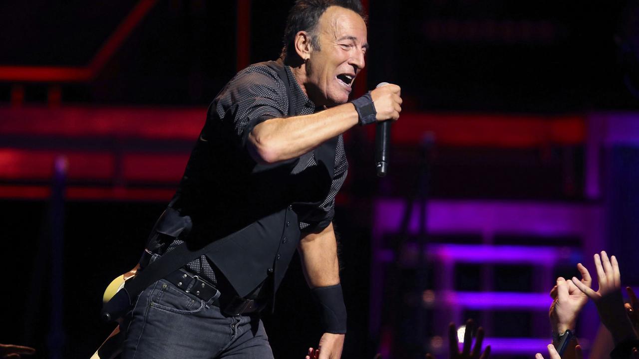 Bruce Springsteen singt bei einem Auftritt während der "River Tour" im Januar 2016 in Chicago auf der Bühne in ein Mikrofon. Hände recken sich ihm entgegen.