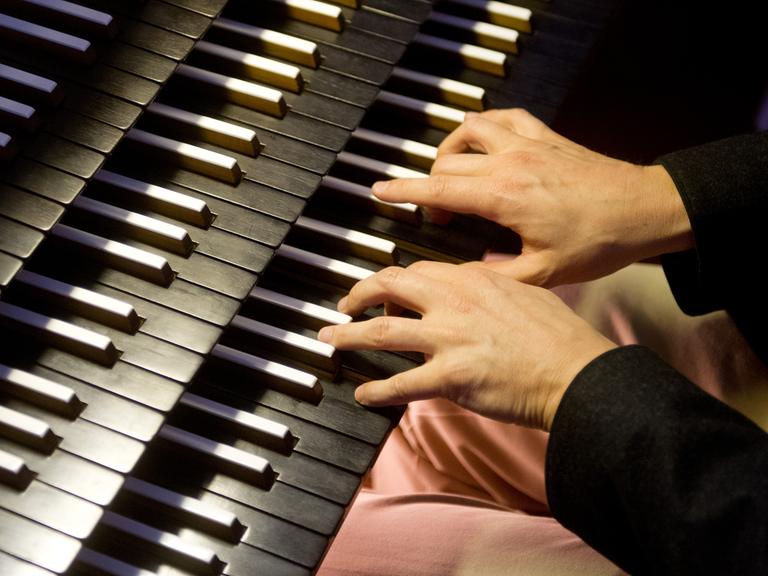 Ein Organist bedient in München in der katholischen Kirche St. Sylvester beim Spielen die Tasten der Orgel.