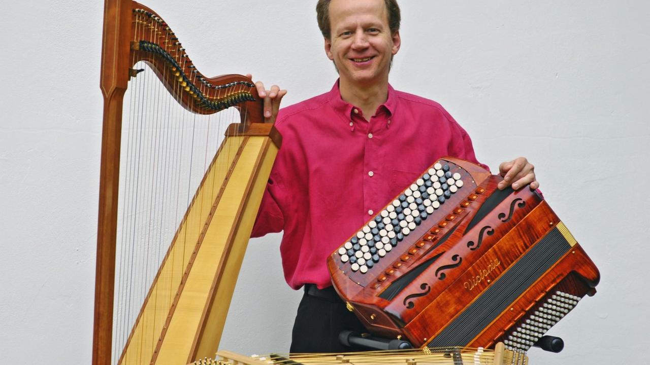 Der Musiker mit Akkordeon, Harfe und Hackbrett im Porträt.
