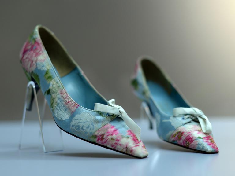 Spitze, mit hellblauem und rosa-farbenem Stoff bezogene Schuhe auf einem Pfennigabsatz von Roger Vivier stehen als Ausstellungsstücke in einer Vitrine im Offenbacher Deutschen Ledermuseum.