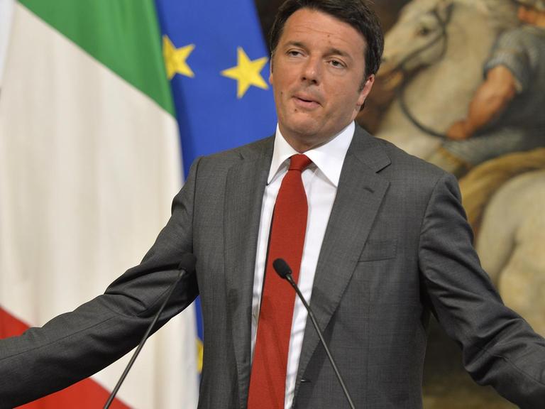 Renzi gestikuliert bei einer Pressekonferenz vor den Fahnen Italiens und Mexikos sowie einem Gemälde mit Reitern.