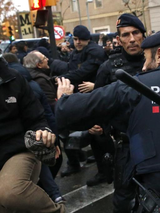 Polizisten der katalanischen Einheit Mossos d'Esquadra halten am 11.12.2017 vor dem Diözesanmuseum der Stadt Lleida in Katalonien (Spanien) wütende Demonstranten zurück.