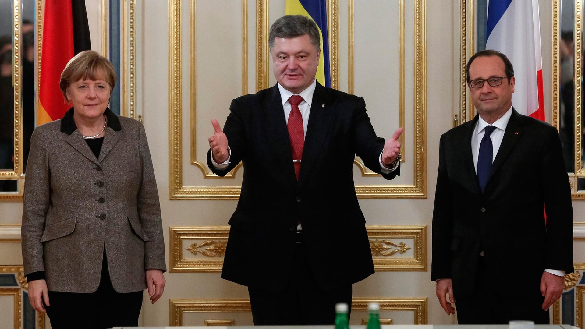 Bundeskanzlerin Angela Merkel (li.) und Frankreichs Präsident Francois Hollande (re.) stehen neben dem ukrainischen Staatsoberhaupt Petro Poroschenko, im Hintergrund sind die Flaggen der drei Länder zu sehen.