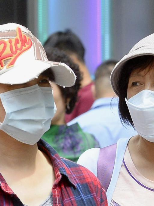Koreaner mit Atem-Schutzmasken in einer Einkaufsgegend von Seoul
