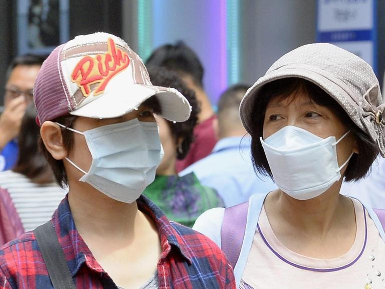 Koreaner mit Atem-Schutzmasken in einer Einkaufsgegend von Seoul