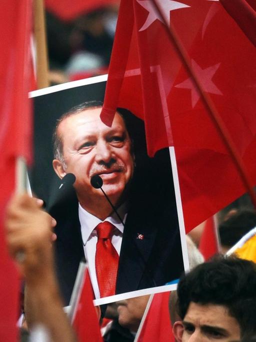 Anhänger des türkischen Staatspräsidenten Recep Tayyip Erdogan halten in Köln Fahnen und ein Bild des Staatschefs.