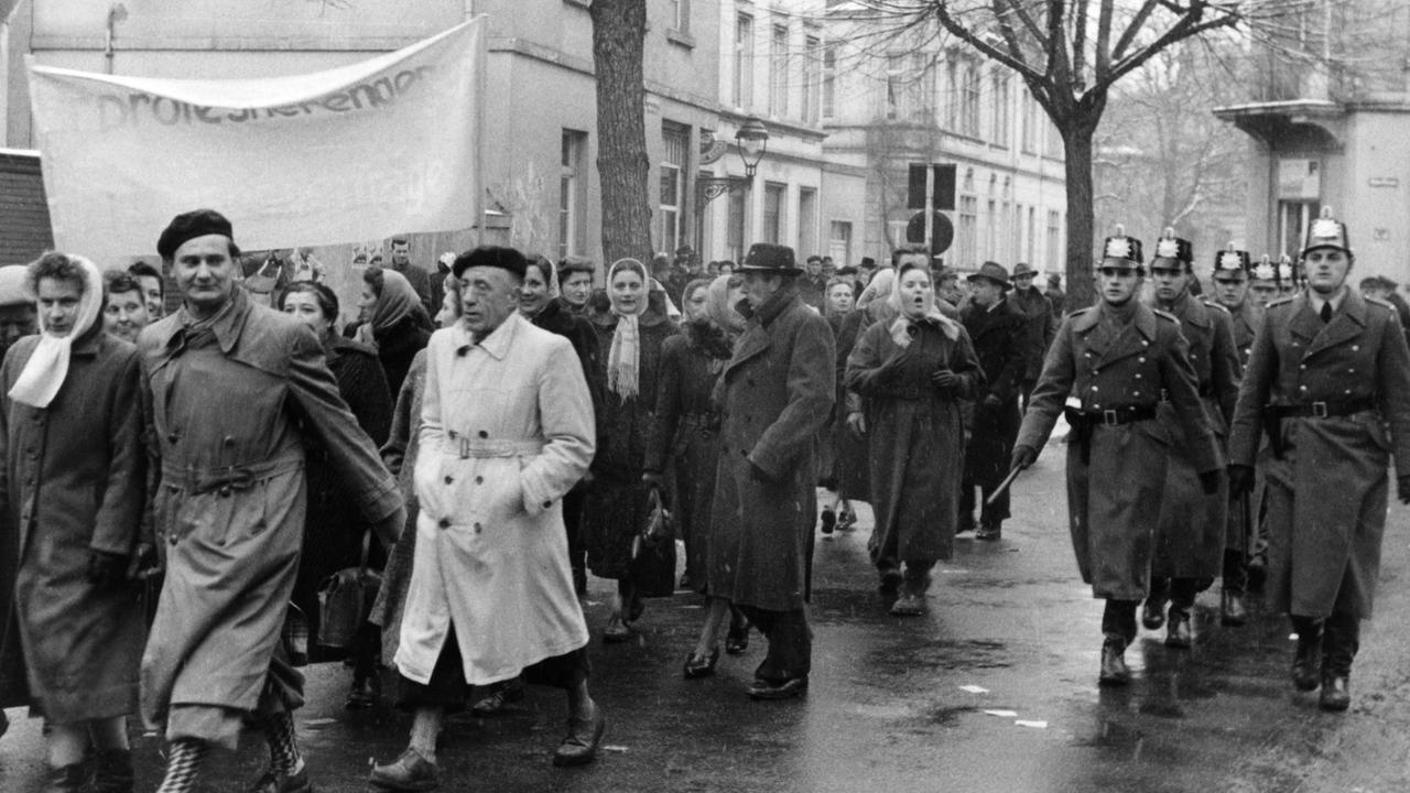 Bei einer Demonstration gegen die Wiederbewaffnung Deutschlands am 24.02.1955 in Bonn laufen Menschen mit Transparenten durch die Straßen.