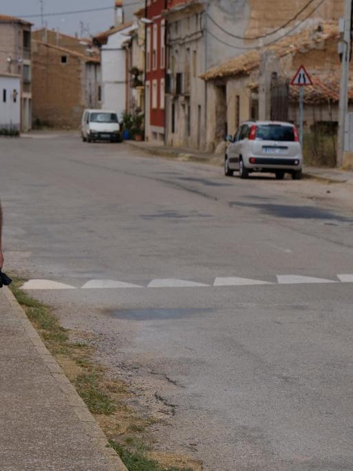 Spanien, die Gemeinde Caminreal östlich von Madrid: Ein Mann spaziert mit seinem Hund eine Straße entlang.