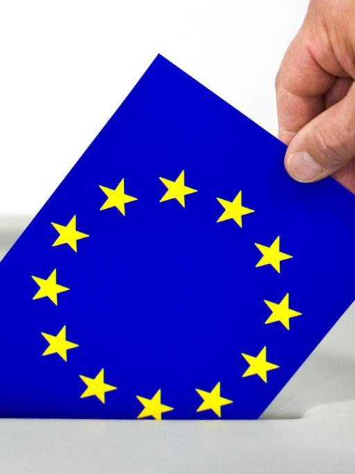 Ein Mann steckt eine Europafahne in den Schlitz einer Wahlurne in Frankfurt (Oder).