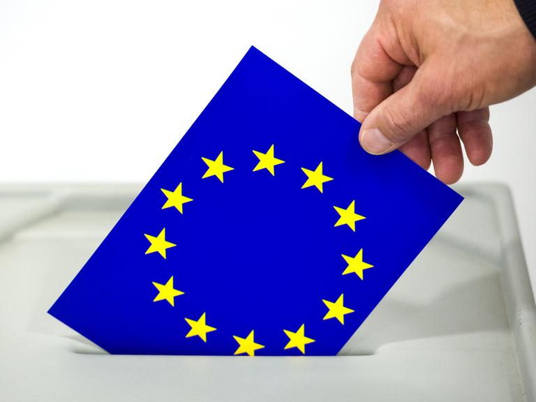 Ein Mann steckt eine Europafahne in den Schlitz einer Wahlurne in Frankfurt (Oder).