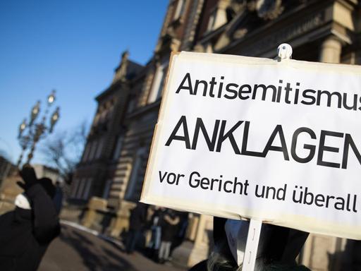Eine Teilnehmerin einer Kundgebung hält ein Schild mit dem Text "Antisemitismus Anklagen vor Gericht und überall" vor dem Strafjustizgebäude in Hamburg. Dort begann gut vier Monate nach dem Angriff auf einen jüdischen Studenten vor der Hamburger Synagoge der Prozess gegen den mutmaßlichen Täter.