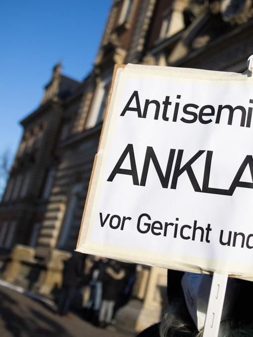 Eine Teilnehmerin einer Kundgebung hält ein Schild mit dem Text "Antisemitismus Anklagen vor Gericht und überall" vor dem Strafjustizgebäude in Hamburg. Dort begann gut vier Monate nach dem Angriff auf einen jüdischen Studenten vor der Hamburger Synagoge der Prozess gegen den mutmaßlichen Täter.