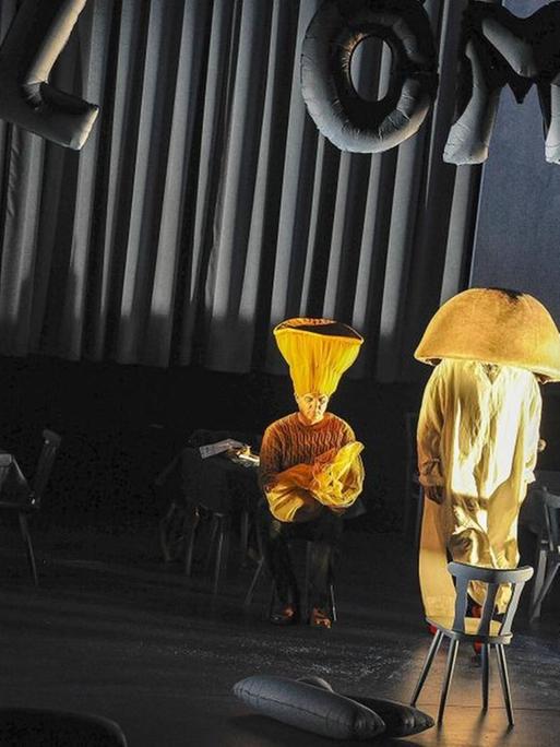 Vier Schauspieler in Gelb als Hand und Stehlampen kostümiert stehen unter dem Schriftzug "Willkommen".