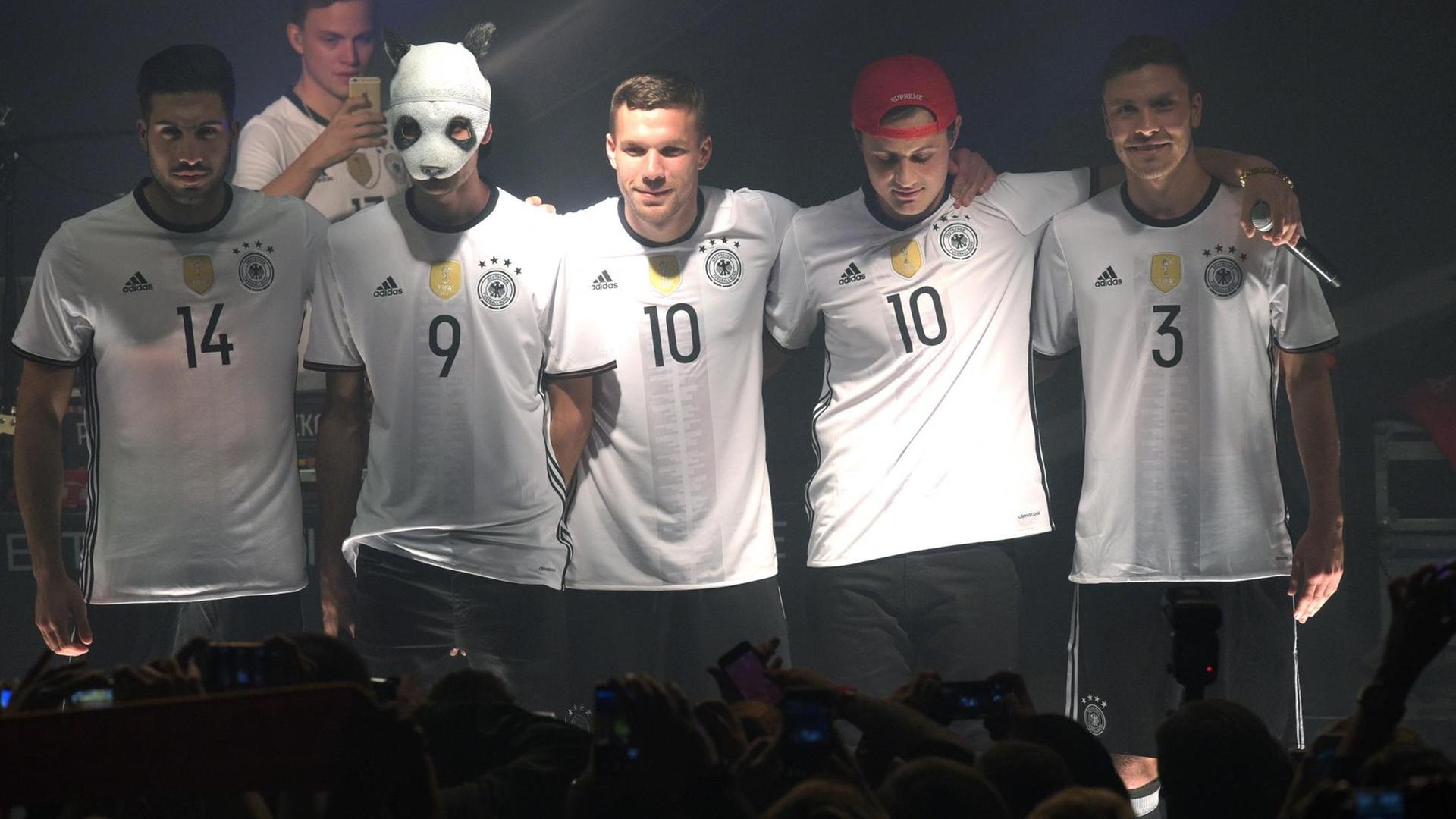 Die Fußballnationalspieler Emre Can (l), Lukas Podolski (M) und Jonas Hector (R) posieren mit Rapper Cro (2.v.l.) am 09.11.2015 in Berlin bei der Trikot-Präsentation des DFB-Ausrüsters Adidas im neuen Trikots der deutschen Nationalmannschaft für die EM 2016 in Frankreich.