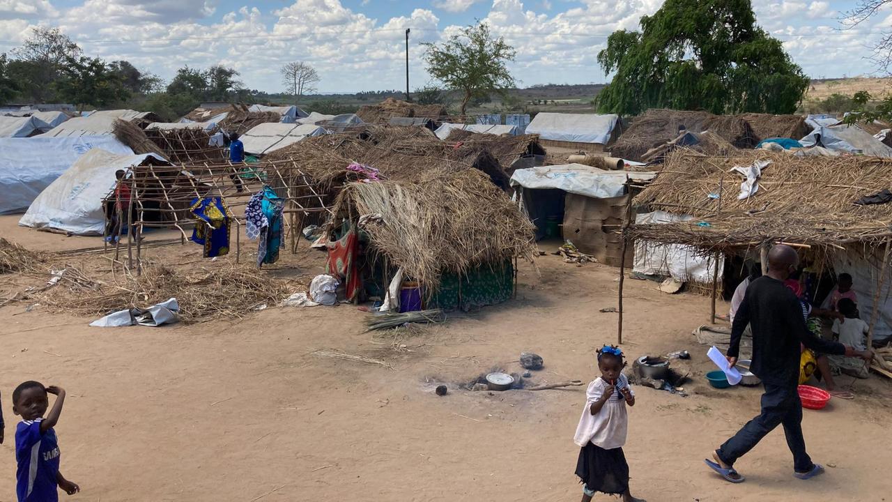 Blick auf das Camp mit teilweise zerstörten Hütten, im Vordergrund laufen Kinder.
