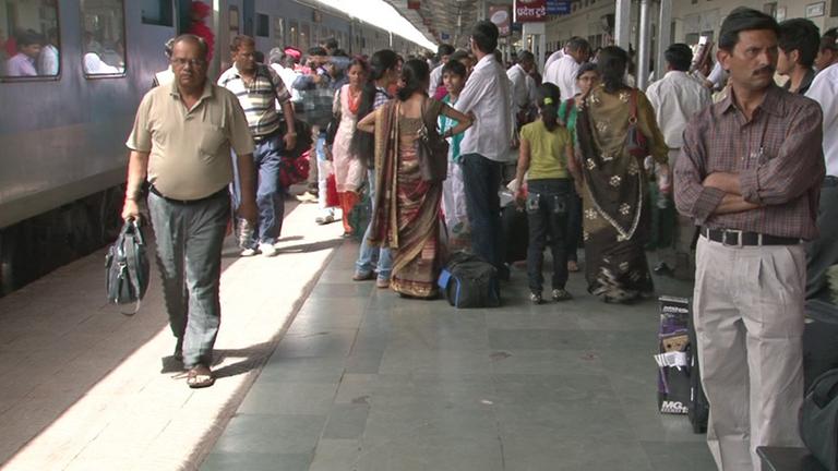 Auf einem Bahnsteig der indischen Hauptstadt Neu-Delhi schieben sich viele Menschen am Gleis entlang.