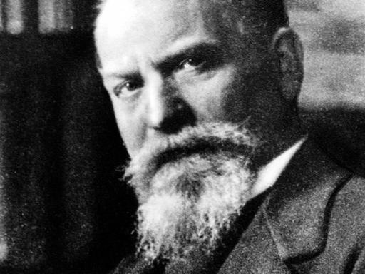 historische Porträtaufnahme von Edmund Husserl vor einer Bucherregal sitzend, um 1930.