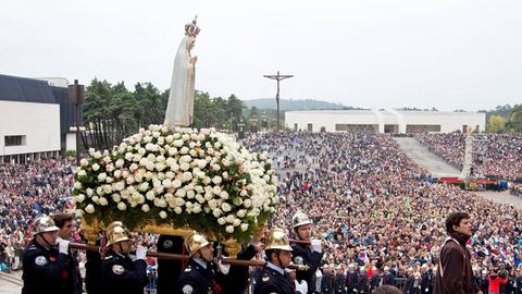 Hunderte Pilger am Schrein der Fatima auf ihrer Wallfahrt am 13.10.2014. Im Vordergrund tragen acht Träger eine Marienstatue auf einer Bahre.