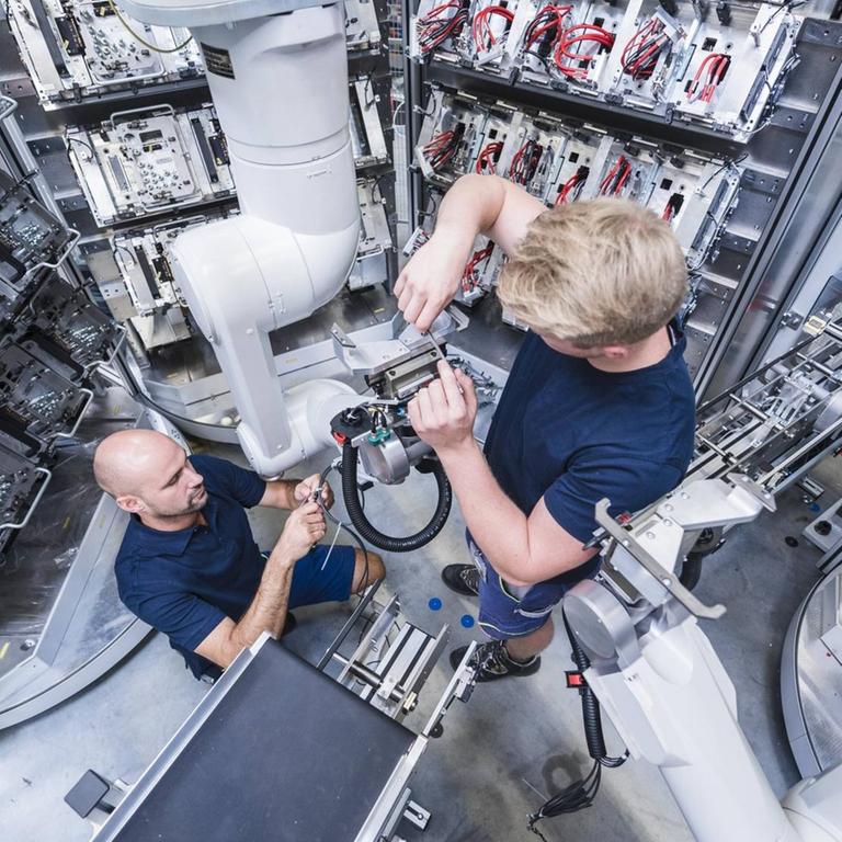 Zwei Männer arbeiten an einem Industrieroboter