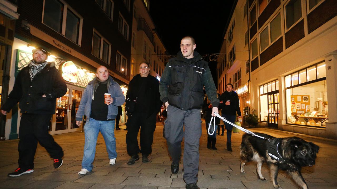 Sympathisanten einer Düsseldorfer Bürgerwehr ziehen im Dunkeln mit einem Hund durch die Altstadt.