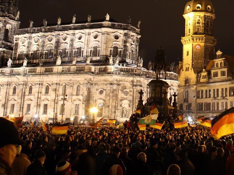 Anhänger des "Pegida"-Bündnisses (Patriotische Europäer gegen die Islamisierung des Abendlandes) demonstrieren in Dresden gegen die angebliche Überfremdung durch Flüchtlinge und schwenken Deutschlandfahnen.