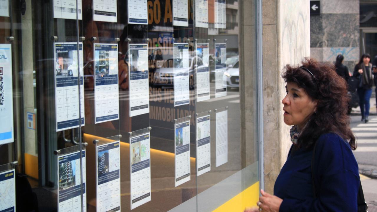 Eine Frau vor dem Fenster eines Maklergeschäfts mit Wohnungsaushängen in Buenos Aires
