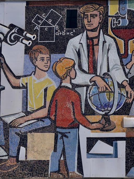 Ein Lehrer im Kreis seiner mit Globus, Mikroskop und Teleskop forschenden Schüler - Mosaik von Walter Womacka an der Fassade des "Haus des Lehrers" am Alexanderplatz in Berlin