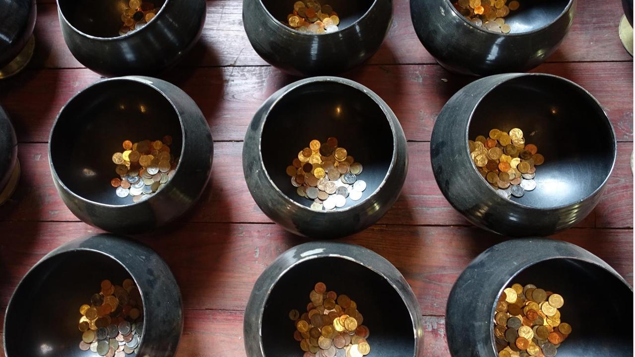 Schalen mit gespendeten Münzen stehen in der Tempelanlage Wat Phan Tao in Chiang Mai, Thailand, aufgenommen am 28.02.2015.