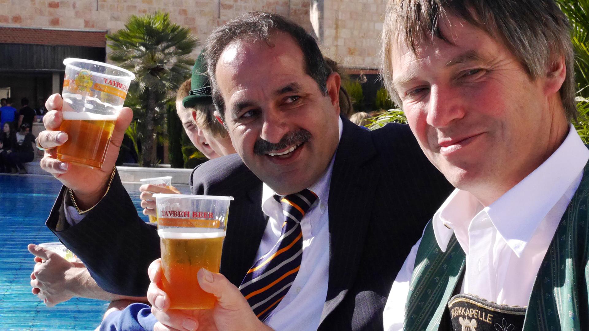 Der Gründer der Taybeh-Brauerei, der Palästinenser Nadim Khoury (l.), lässt sich beim Oktoberfest in Ramallah zusammen mit dem Blasmusiker Christian Helinger sein Bier schmecken; Aufnahme vom Oktober 2013