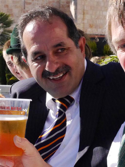 Der Gründer der Taybeh-Brauerei, der Palästinenser Nadim Khoury (l.), lässt sich beim Oktoberfest in Ramallah zusammen mit dem Blasmusiker Christian Helinger sein Bier schmecken; Aufnahme vom Oktober 2013