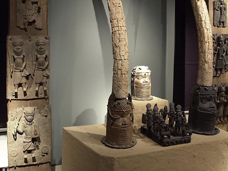 In einer Ausstellung von Kunstwerken aus dem früheren Königreich Benin sind Skulpturen, Elefantenstoßzähne und Wandplatten zu einem Altar auf einer Lehmplattform zusammengestellt.