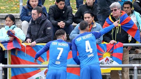 Necmi Gür (li) und Nenad Simic von Schott Mainz sprechen mit Zuschauern, die aus Protest gegen die chinesiche Tibet-Politik Fahnen des Nachbarlands von China auf der Tribüne hochhalten. Die Spieler der chinesichen U-20-Nationalmannschaft verließen daraufhin aus Protest den Platz. Foto: Hasan Bratic/dpa | Verwendung weltweit
