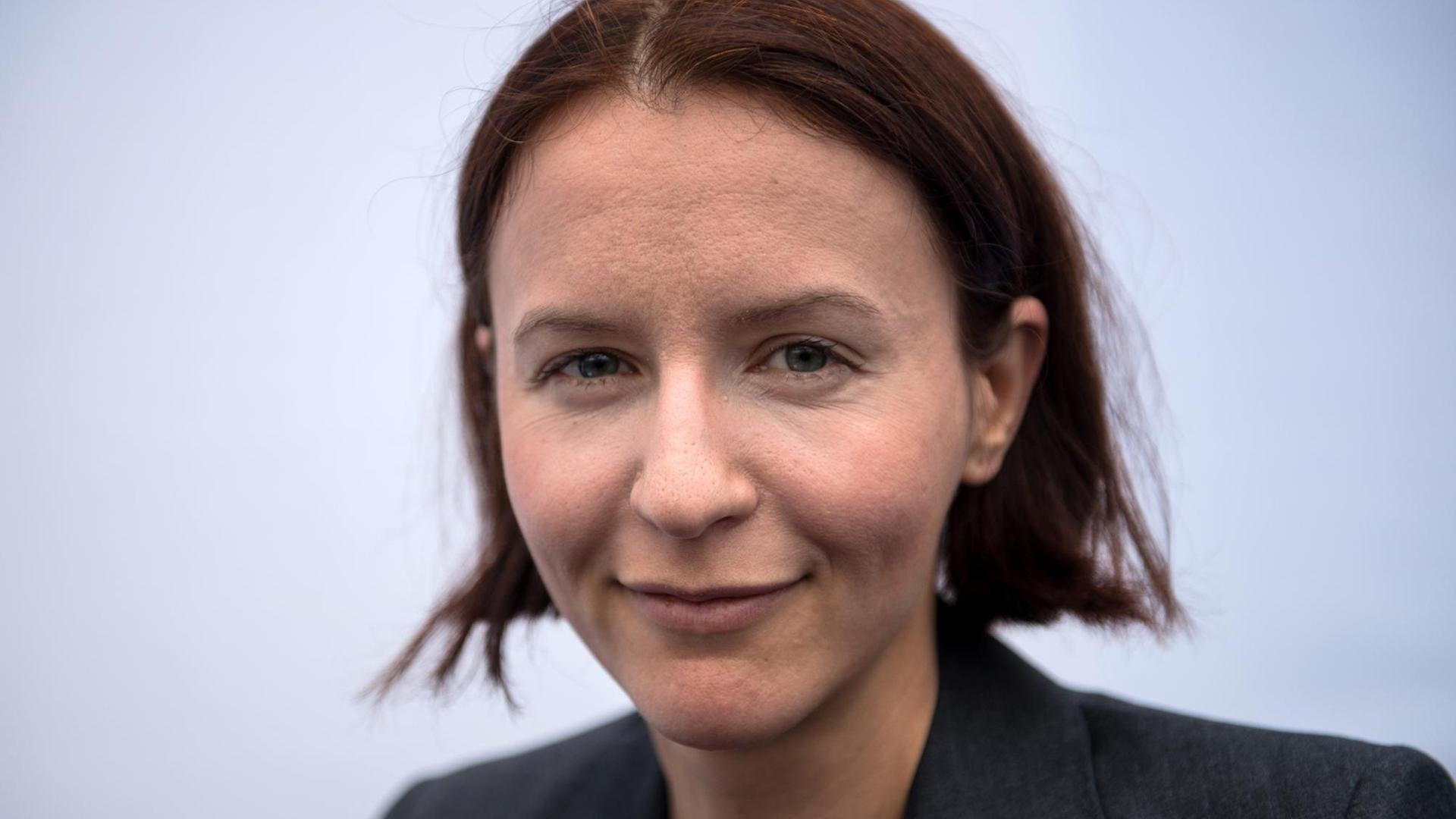 Die deutsche Schriftstellerin Alina Bronsky blickt, verschmitzt lächelnd direkt in die Kamera.
