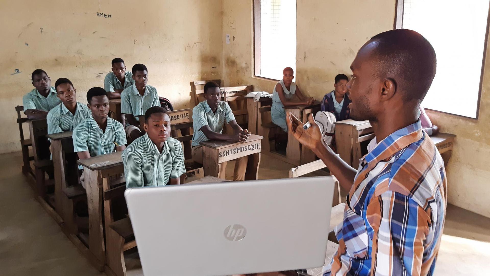 Der Lehrer Earnest Adomensa zeigt den Schülerinnen und Schülern das Microsoft Startmenü auf seidem privaten Laptop.