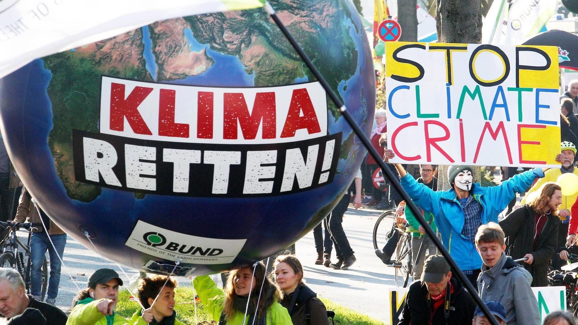 Demonstranten fordern am 04.11.2017 in Bonn (Nordrhein-Westfalen) mit einem Modell der Erdkugel mit der Aufschrift "Klima retten" die Umsetzung des Weltklimaabkommens.
