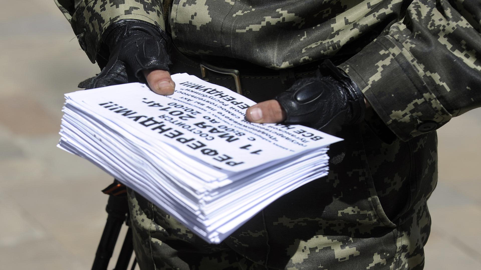 Ein Mitglied der sogenannten Volksarmee in der Ostukraine hält Einladungen zum Referendum über die Unabhängigkeit der Regionen Donezk und Lugansk in den Händen.