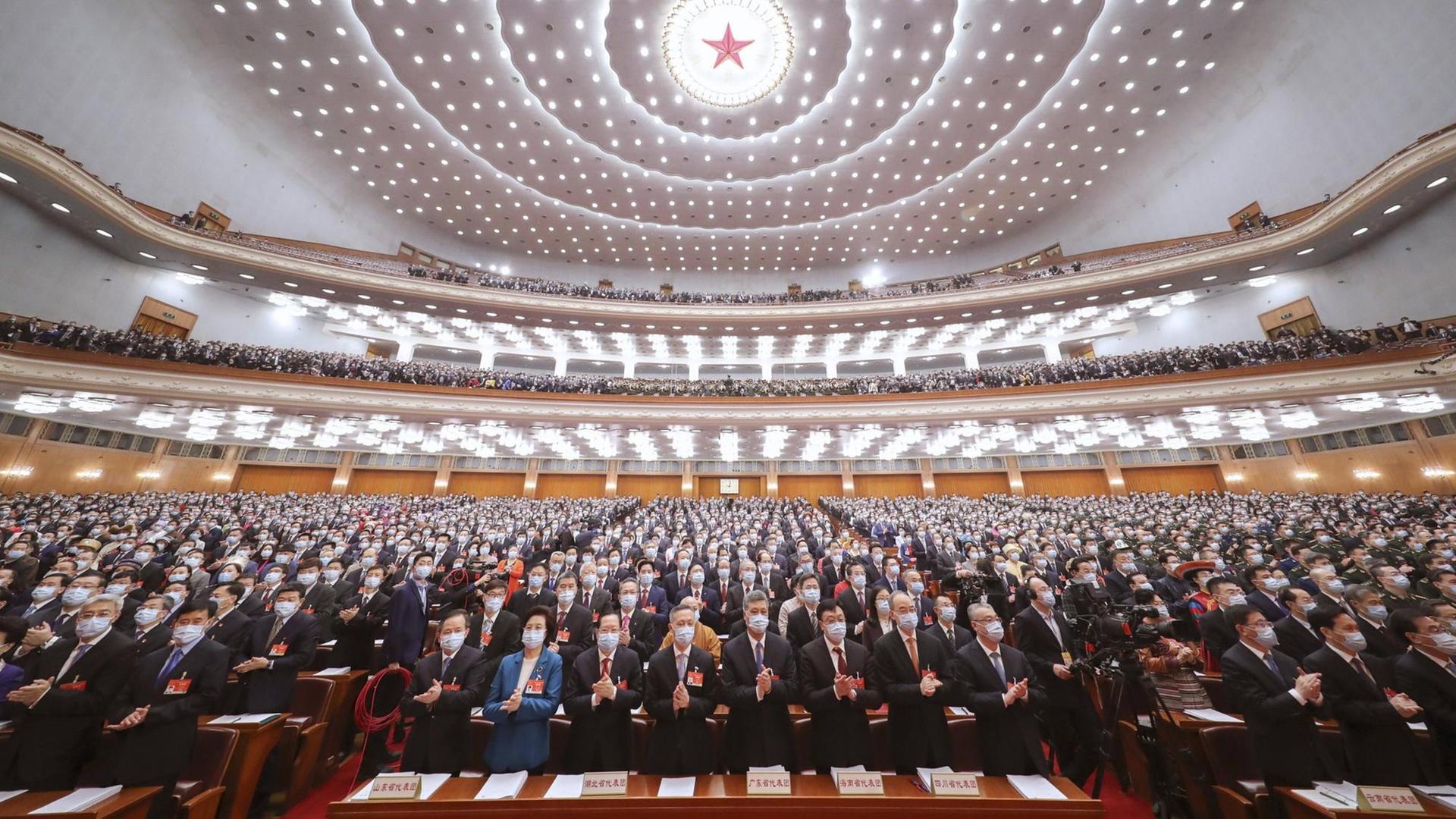 Beim 13. Nationale Volkskongress in China in Peking stehen die Teilnehmer auf und klatschen.