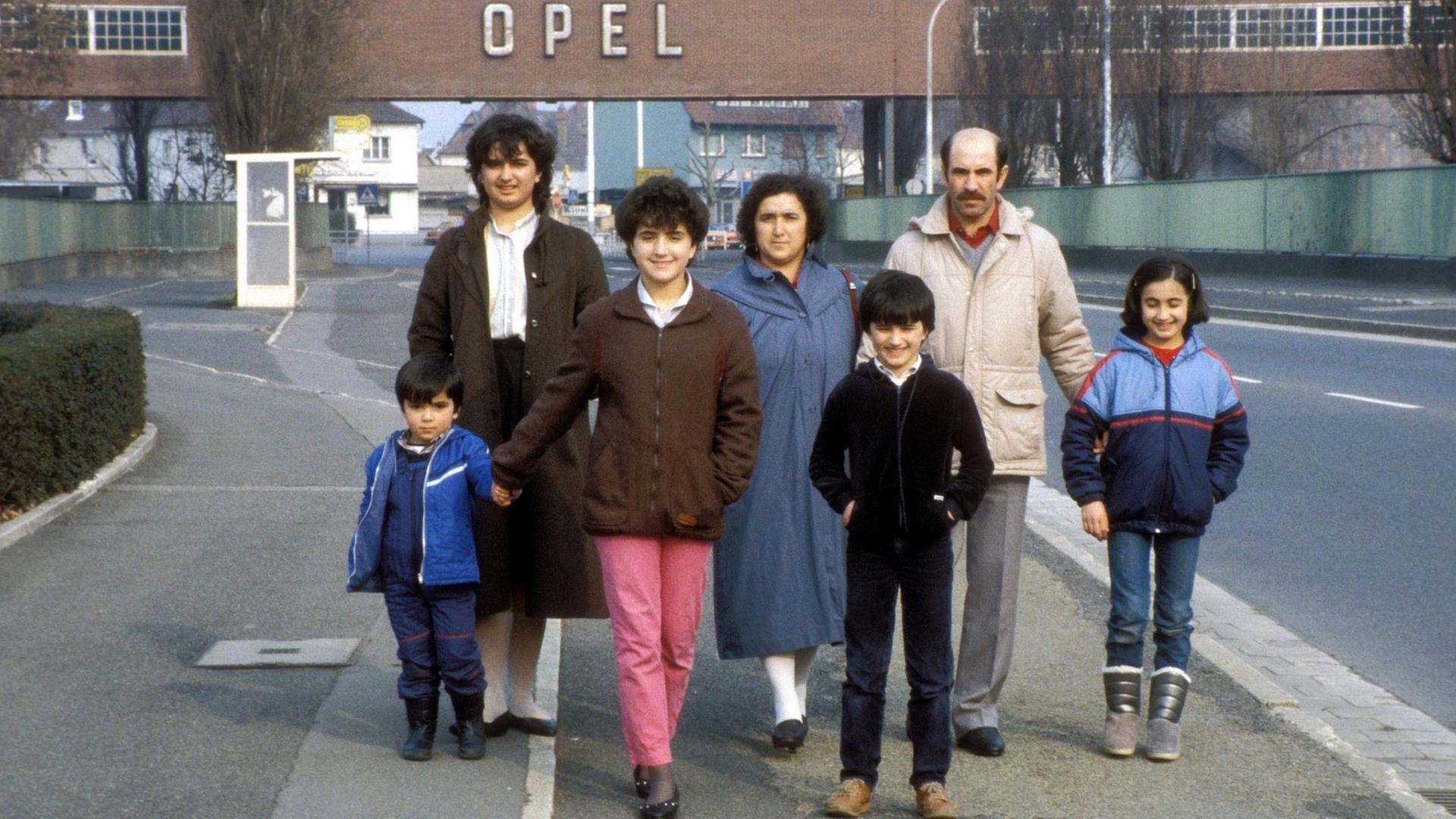 Eine türkische Gastarbeiterfamilie steht vor dem Tor der Opel-Werke in Rüsselsheim im Jahr 1984.