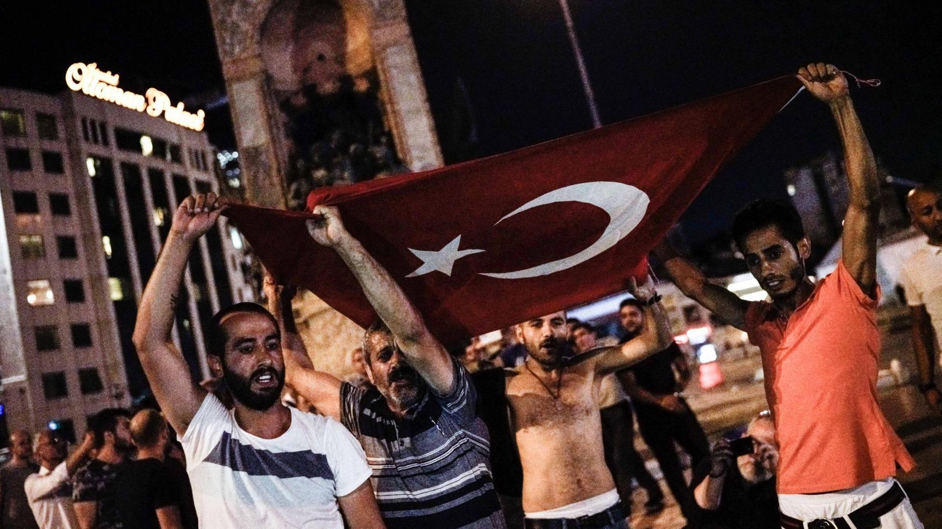 Männer tragen eine türkische Flagge auf dem Taksimplatz in Istanbul.